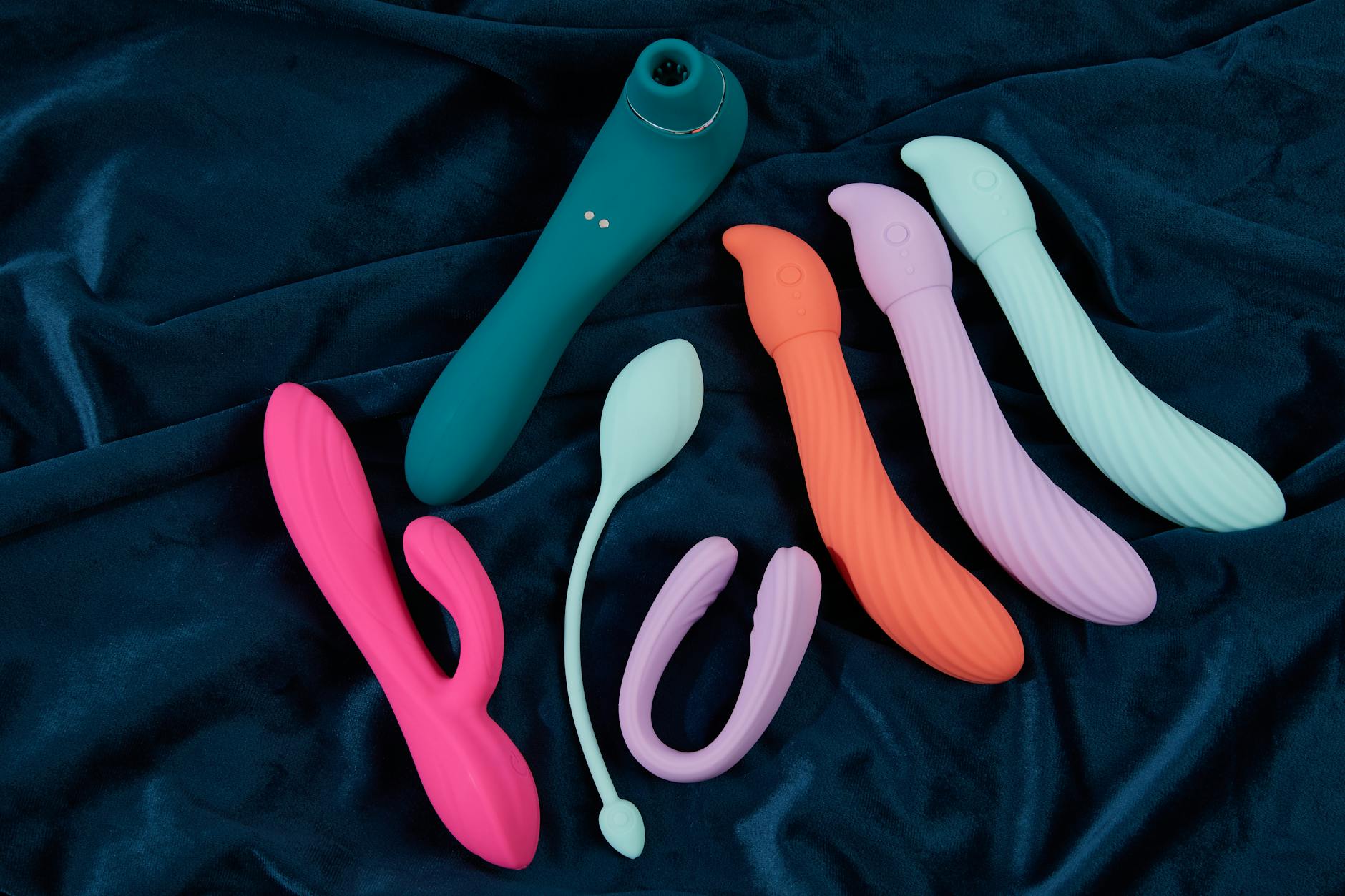 A blue silicone clitoral vibrator held in hand against a purple background, promoting self-love and sexuality.