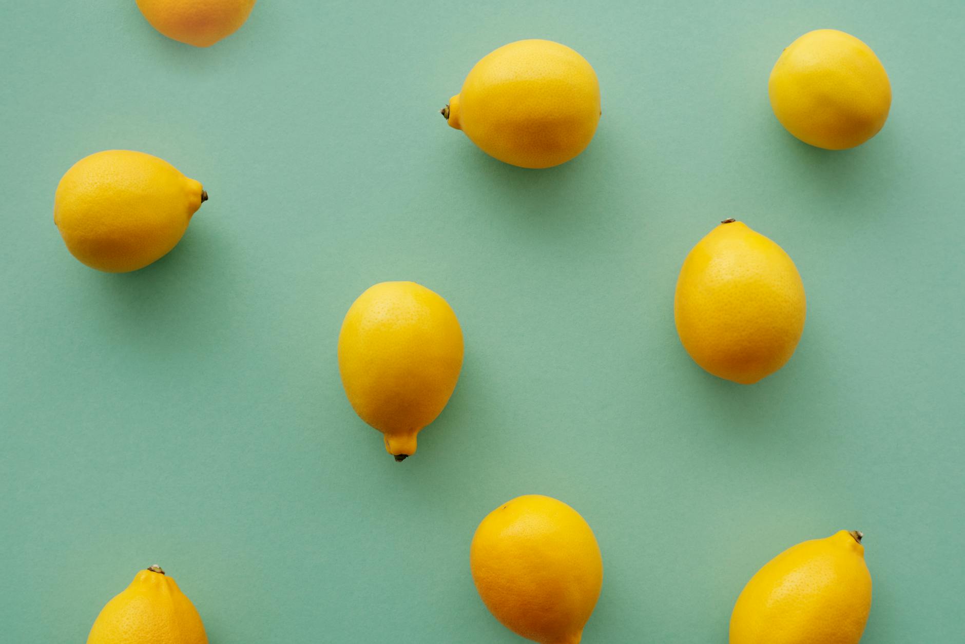 A hand holding a lemon against a bright yellow background, symbolizing fresh pleasure and vitality