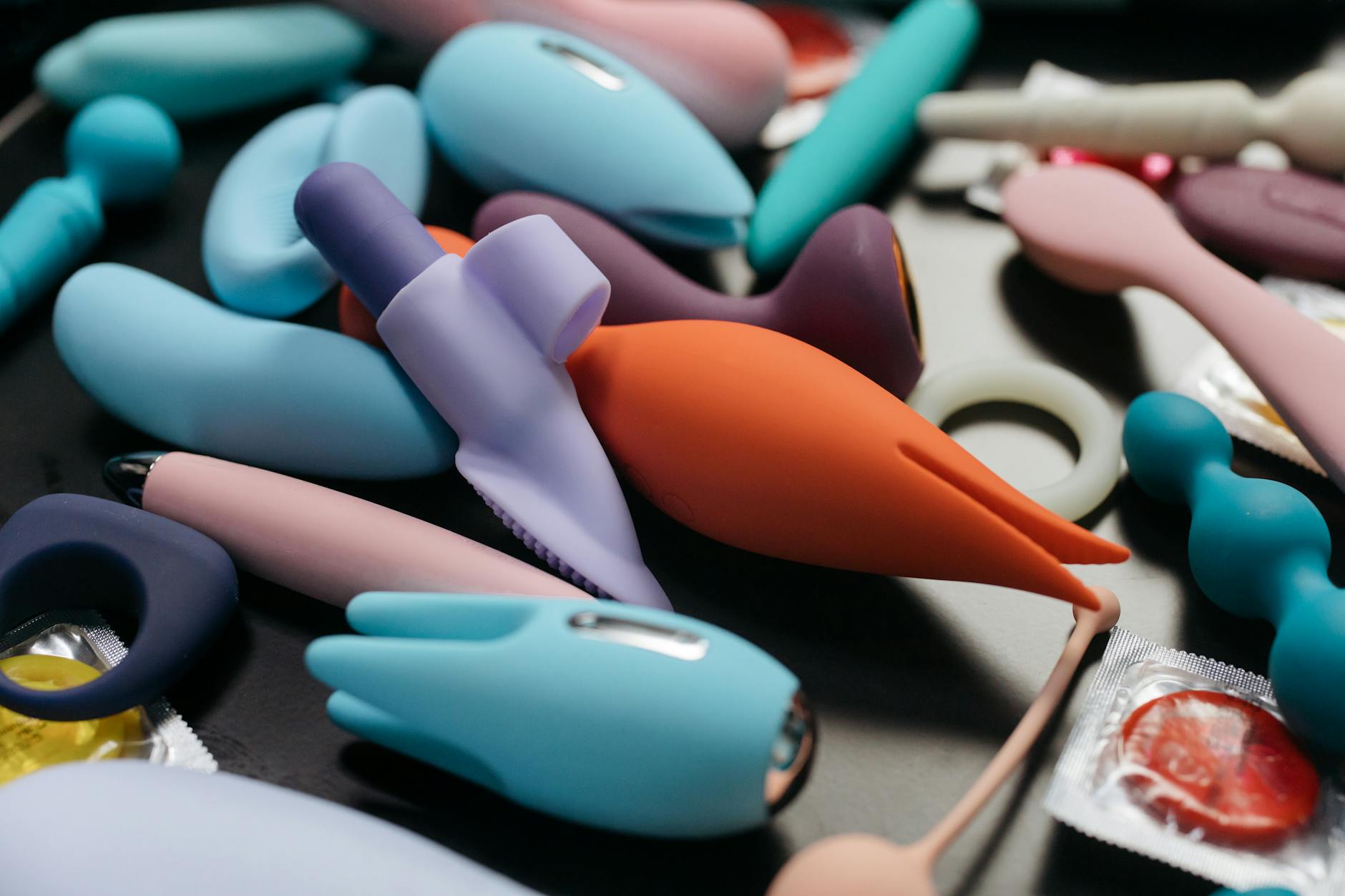 Hand holding an orange vibrator against a minimalistic purple backdrop