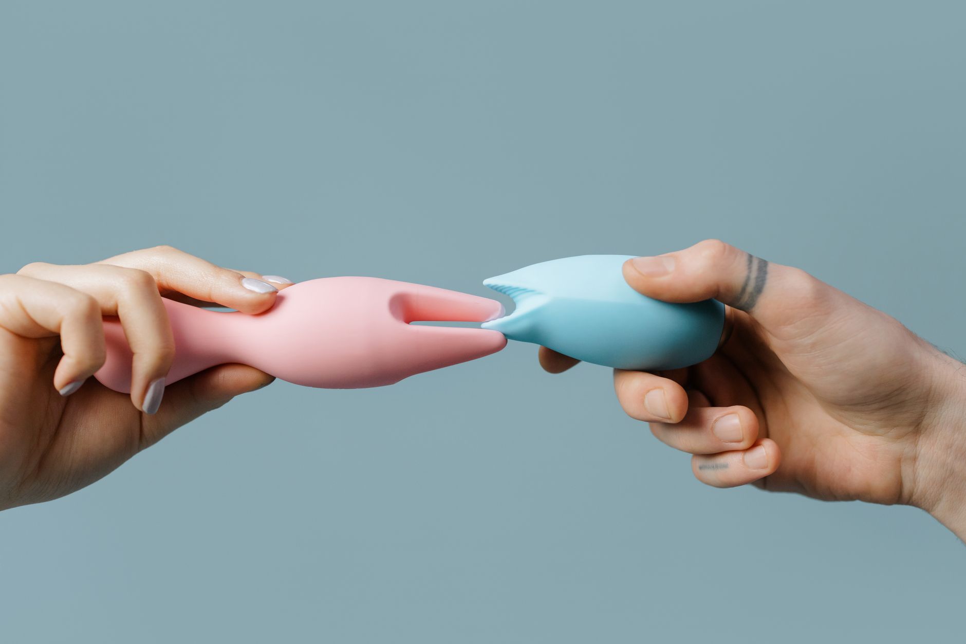 Hands holding pastel silicone vibrators for intimate wellness