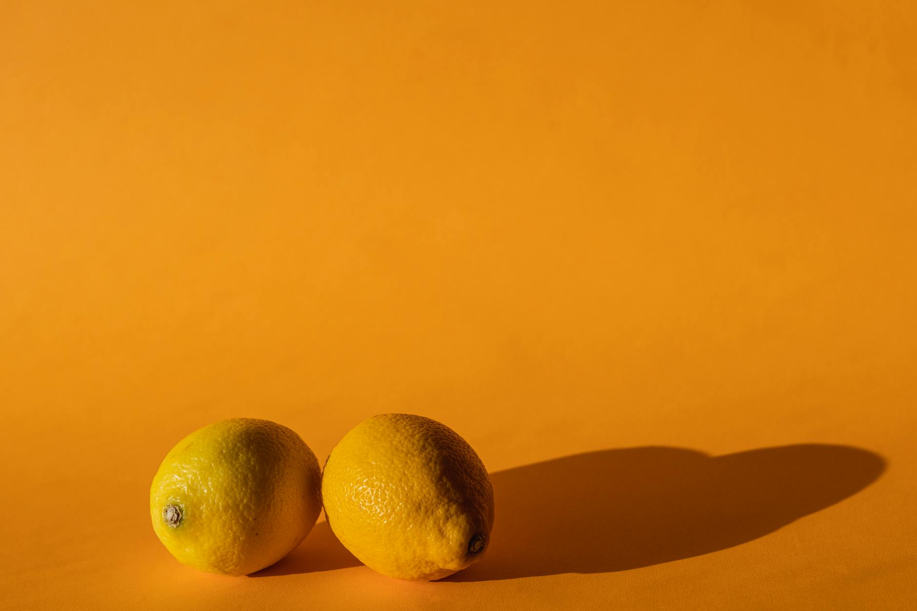 Ripe yellow lemons on a bright yellow background, symbolizing cyclical nature and feminine rhythm